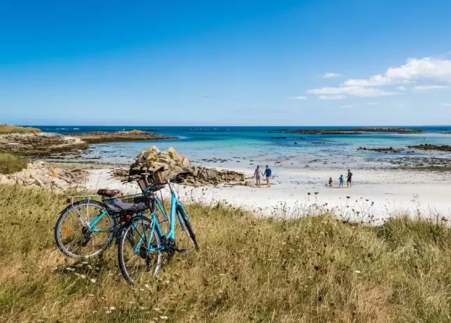 Deux vélos posés face à une plage sauvage près de Bénodet, cadre idéal pour une balade depuis un camping Bénodet entre nature et océan.